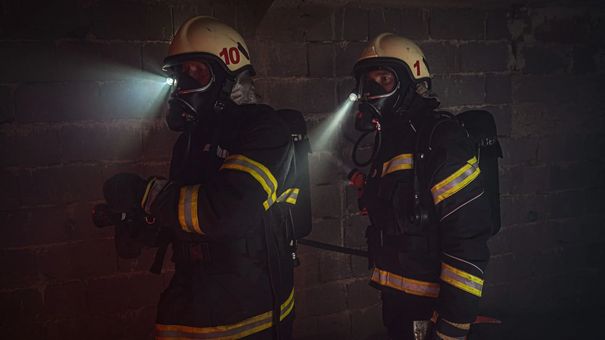Bomberos con linternas avanzando en un ambiente con humo