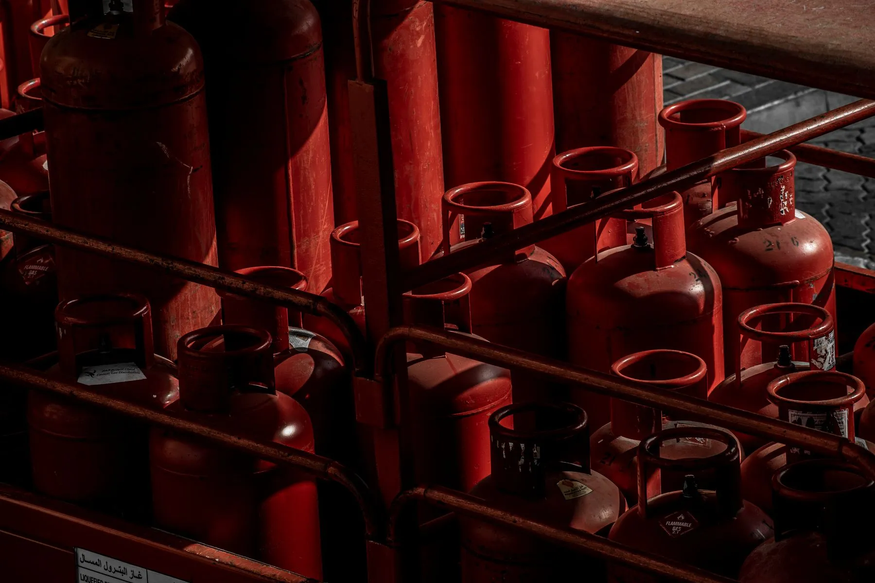 Cilindros rojos de alta presión acomodados en un rack metálico para su revisión