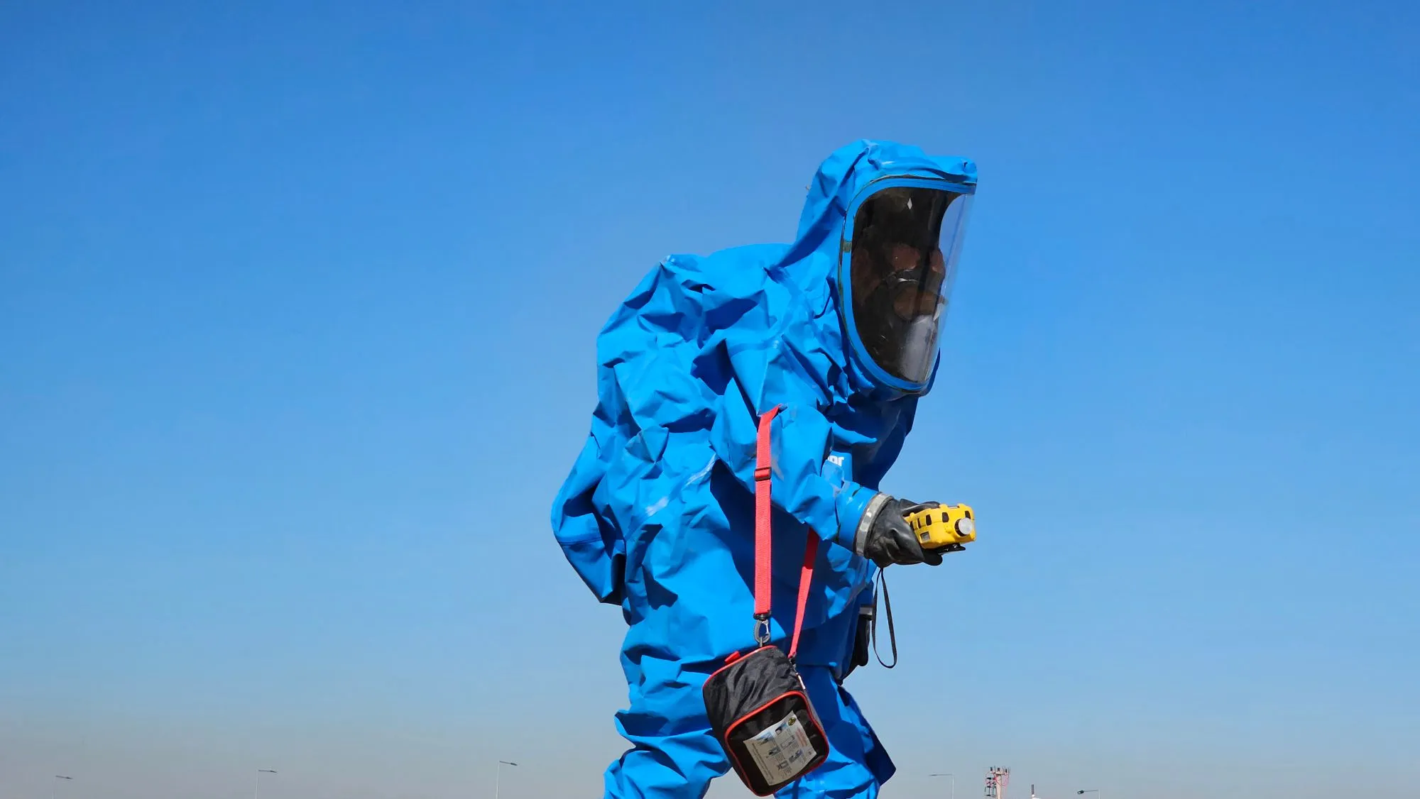 Persona con traje de protección química azul y detector portátil